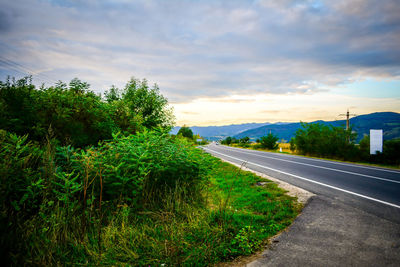 Country road against cloudy sky