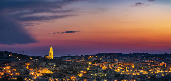 Aerial view of illuminated city against sky during sunset