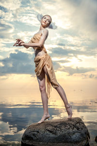 Woman standing on beach against sky during sunset