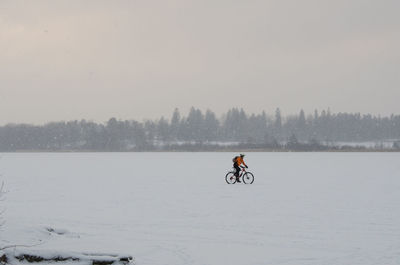 Side view of a man bicycling on snowed landscape