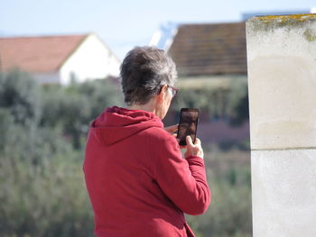 Rear view of senior man taking selfie on mobile phone