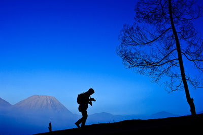 Man standing on mountain against clear blue sky