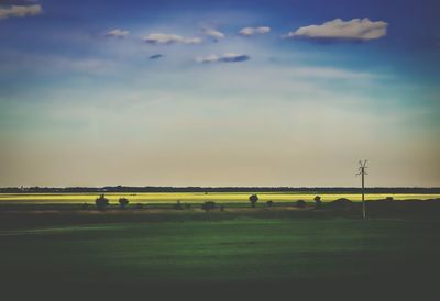 Scenic view of grassy field against cloudy sky