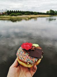 Midsection of person holding donut in lake