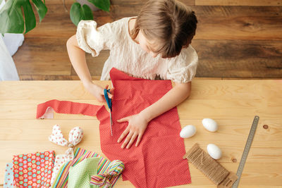 Home decoration for easter. top view of a girl who makes eggs from a fabric in the shape of a hare 