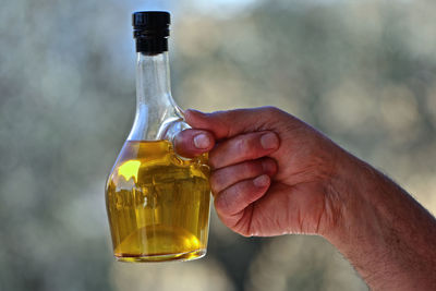 Midsection of person holding glass bottle