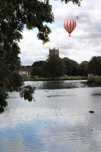 Hot air balloon flying over lake against sky