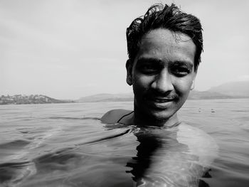 Close-up of smiling man in sea against sky