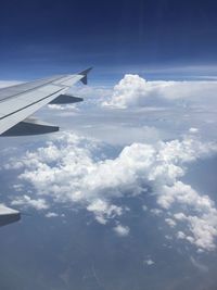 Cropped image of airplane wing over clouds
