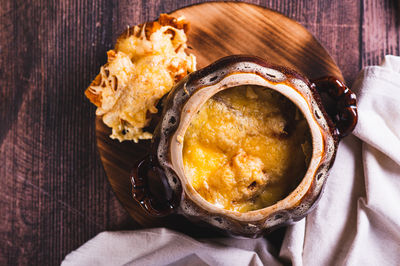 Close up of french onion soup with melted cheese and croutons in a pot on the table top view