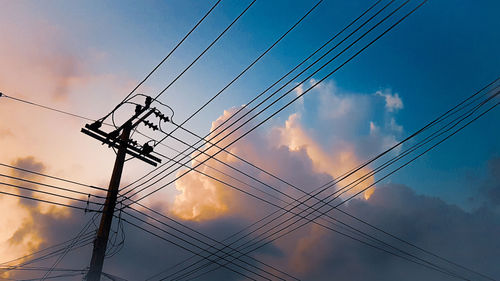 Low angle view of power lines against cloudy sky