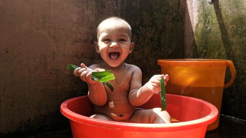 Portrait of boy holding leaves while sitting in tub