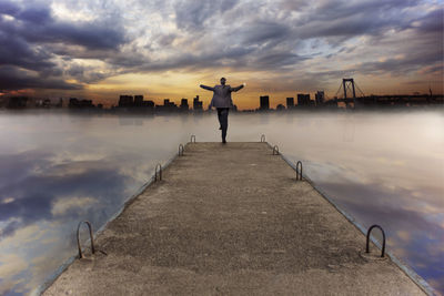 Silhouette of woman in sea against cloudy sky