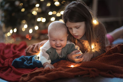 Girl and a younger sister, the baby is crying, and her sister feels sorry for her and comforts her. 