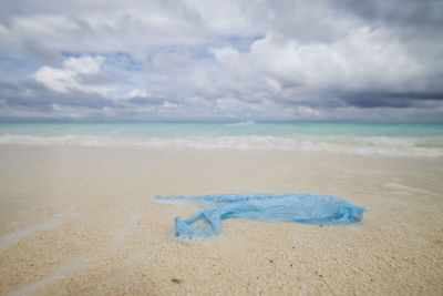 Abandoned plastic bag on sand beach against sea. themes ocean pollution and environmental issues.