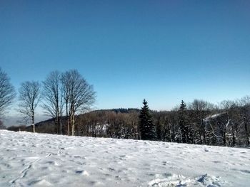 Snow covered field against clear blue sky