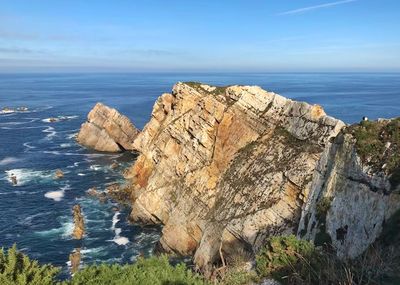 Rock formation in sea against blue sky