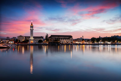 Illuminated buildings in city at sunset