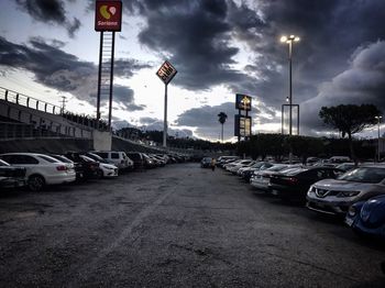 Cars on road in city against cloudy sky