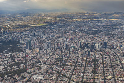 High angle view of city buildings against cloudy sky