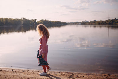 Full length of woman standing by lake against sky