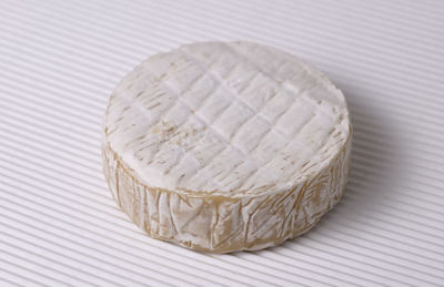 Round brie cheese out over white corrugated background, close up view.