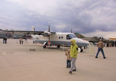 People at airport runway against sky