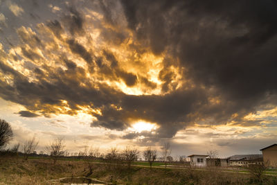 Scenic view of dramatic sky over land during sunset