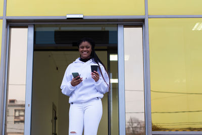 Full length of smiling young man using mobile phone