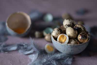 Quail eggs in ceramic vases, gray feathers on the table, easter still life,