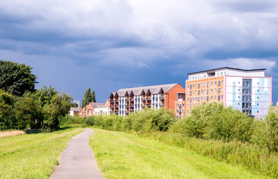 Footpath amidst houses and buildings against sky