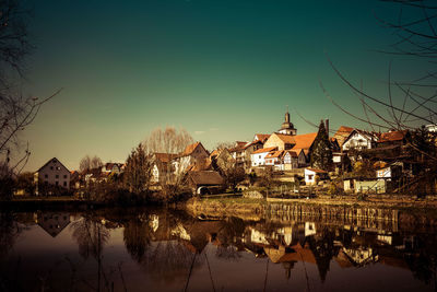 High angle view of townscape by lake against sky at sunset