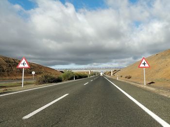 Empty road by landscape against sky