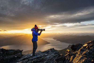 Figure with camera above queenstown and lake, remarkables new zeala