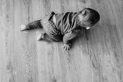 High angle view of baby girl crawling on hardwood floor