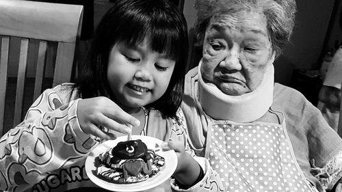 Close-up of girl holding food in plate by grandmother at home