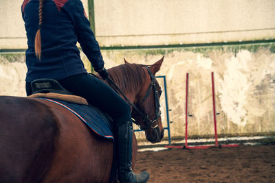 Midsection of woman riding horse outdoors