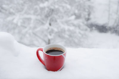 Close-up of coffee cup on snow covered table during winter