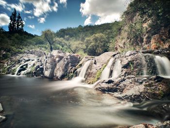 Scenic view of waterfall against sky