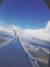 Aerial view of aircraft wing over landscape against blue sky