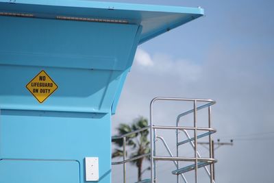 Close-up of information sign on lifeguard hut against sky