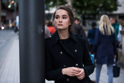 Young woman looking away while standing in city