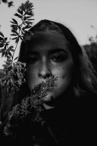 Close-up portrait of young woman against plants