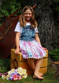 Portrait of smiling girl sitting on wooden crate in back yard