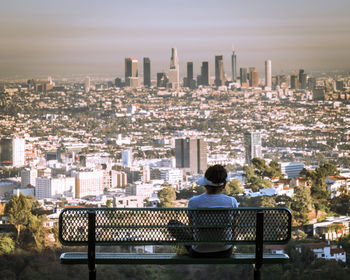 Rear view of man sitting against cityscape