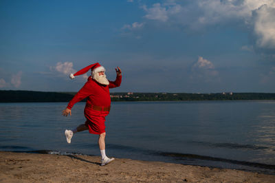 Full length of boy standing at beach against sky