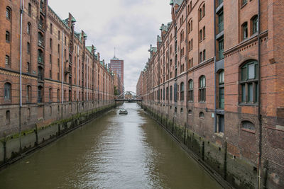 Canal amidst buildings in city against sky