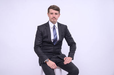 Portrait of young man standing against white background