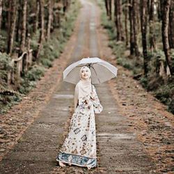 Full length of woman wearing hat on footpath in forest