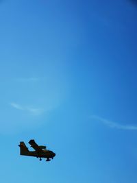 Low angle view of airplane flying against blue sky